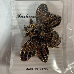 Rhinestone bee brooch pin with black and amber crystals, set in gold tone metal.
